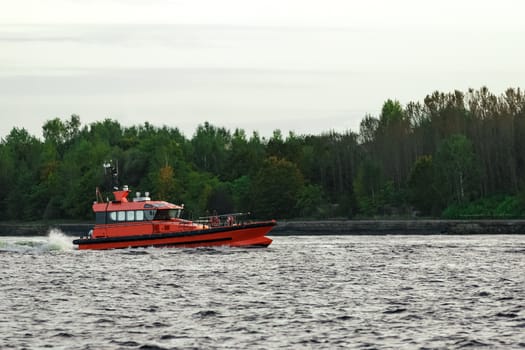 Orange pilot ship sailing on the Daugava river