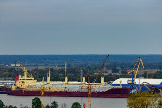 Red cargo ship loading in port at Riga city, Latvia