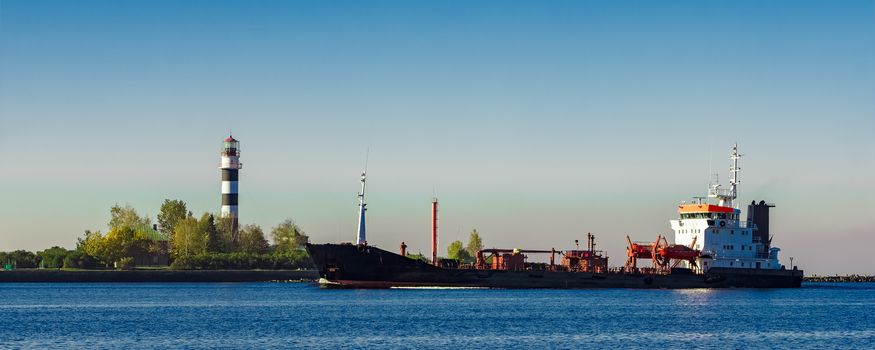 Black cargo oil tanker entering the port of Riga at sunny day