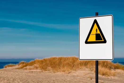 Yellow warning sign on summer beach, Riga