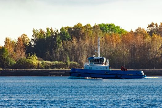 Blue small tug ship leaving Riga and entering the Baltic sea