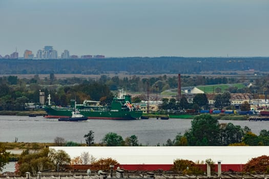 Tug ship moving past the cargo port at Riga city