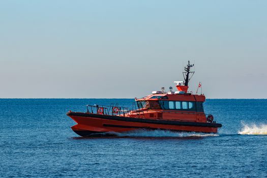 Orange pilot ship moving fast from Baltic sea