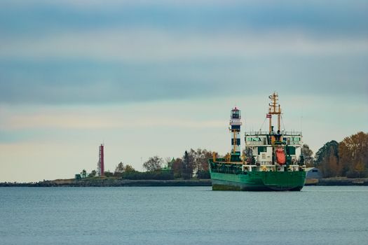 Green cargo ship moving to the port in cloudy day