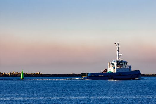 Blue small tug ship leaving Riga and entering the Baltic sea