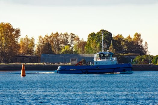 Blue small tug ship leaving Riga and entering the Baltic sea