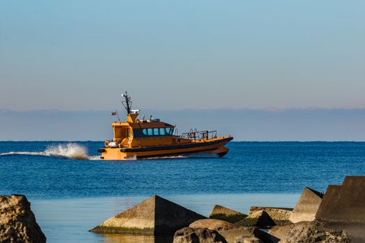 Yellow pilot ship moving at speed from the Baltic sea