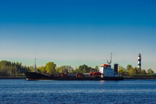 Black cargo oil tanker entering the port of Riga at sunny day