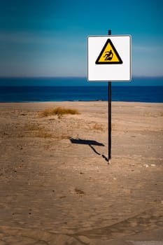 Yellow warning sign on summer beach, Riga