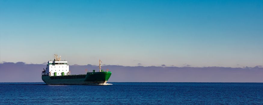 Green cargo ship moving in still water of Baltic sea