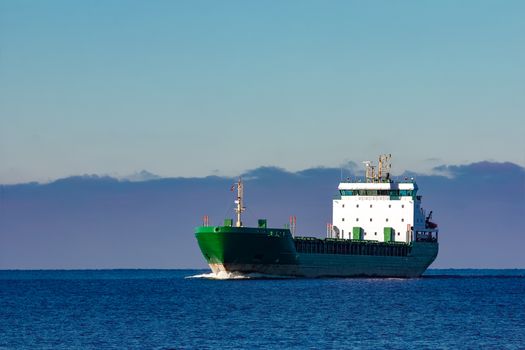 Green cargo ship moving in still water of Baltic sea