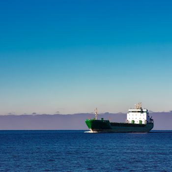 Green cargo ship moving in still water of Baltic sea