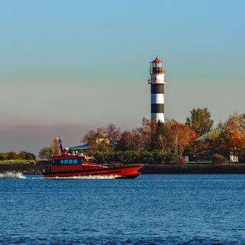 Red pilot ship moving past the lighthouse in Riga