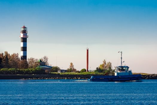 Blue small tug ship leaving Riga and entering the Baltic sea