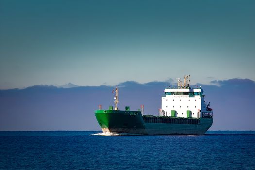 Green cargo ship moving in still water of Baltic sea