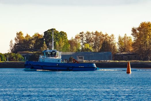 Blue small tug ship leaving Riga and entering the Baltic sea