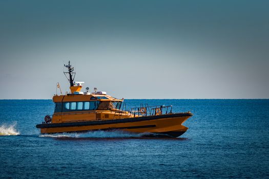 Yellow pilot ship moving at speed from the Baltic sea