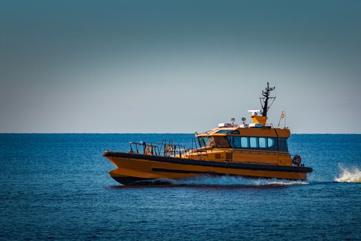 Yellow pilot ship moving at speed from the Baltic sea