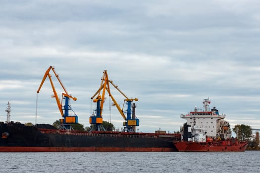 Black cargo ship loading in the port of Riga, Europe