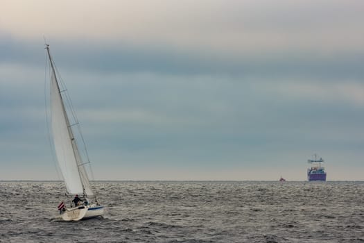 White sailboat traveling in Baltic sea in cloudy day