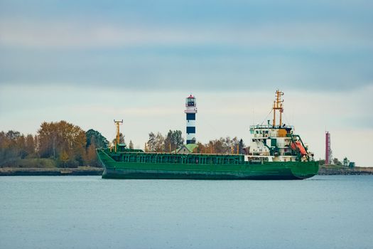 Green cargo ship moving to the port in cloudy day