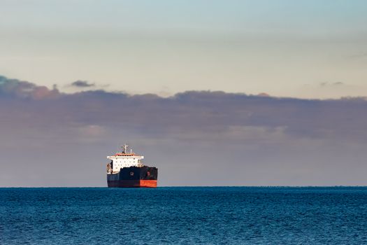 Black cargo ship moving in still Baltic sea water. Riga, Europe