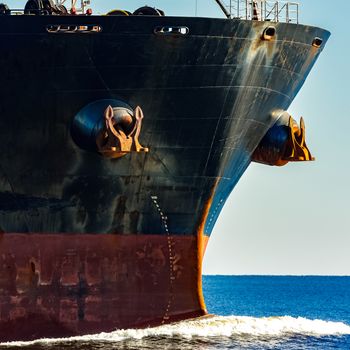 Black cargo ship's bow in still water. Riga, Europe