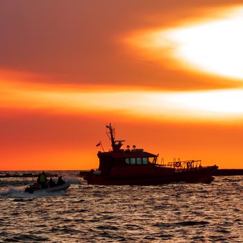 Pilot ship and the dinghy on speed during hot sunset, Latvia