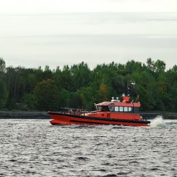 Orange pilot ship sailing on the Daugava river