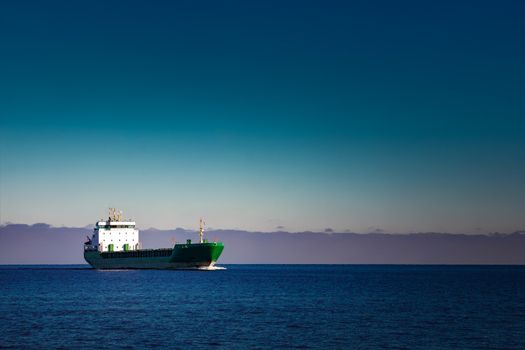 Green cargo ship moving in still water of Baltic sea