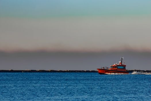 Red pilot ship moving past the breakwater dam in Riga, Europe