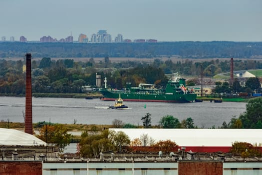 Tug ship moving past the cargo port at Riga city