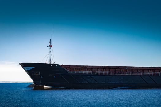 Black cargo ship's bow. Bulk carrier sailing in still Baltic sea