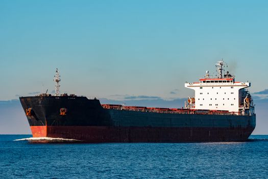 Black cargo ship moving in still Baltic sea water. Riga, Europe