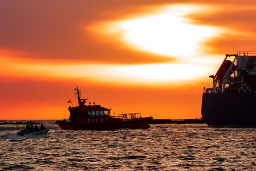 Pilot ship catches big container ship during hot sunset, Latvia