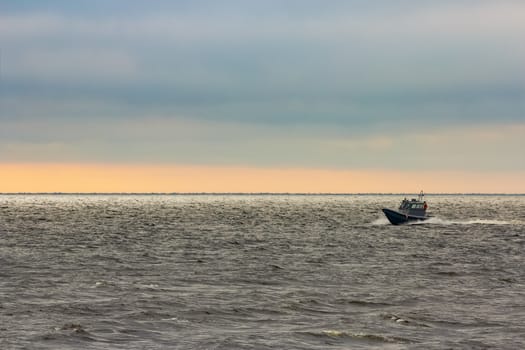 Small grey border guard boat moving fast in still evening