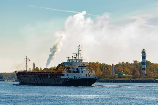 Black cargo ship with long reach excavator moving by Baltic sea