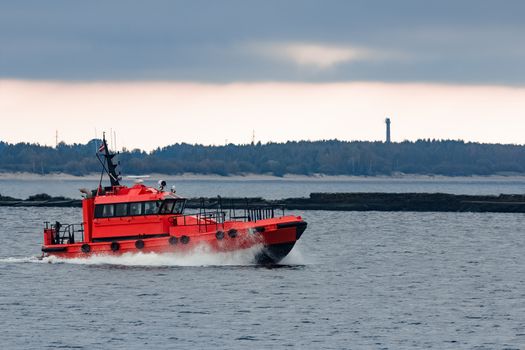 Red pilot ship moving at speed to Baltic sea in Riga, Europe