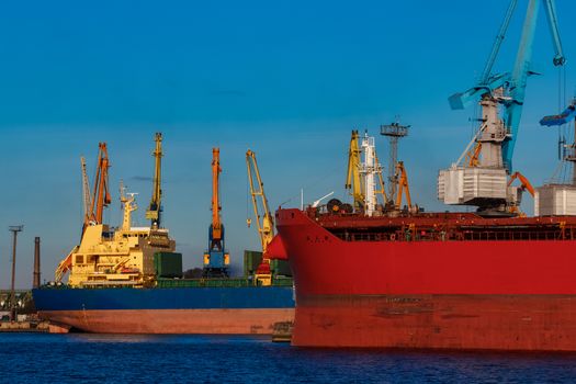 Red and blue cargo ship loading in the port of Riga