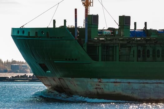 Green cargo ship's bow close up in still water, Riga