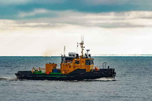 Small orange tug ship moving from the Baltic sea