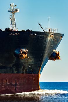 Black cargo ship's bow in still water. Riga, Europe