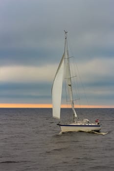 White sailboat traveling in Baltic sea in cloudy day