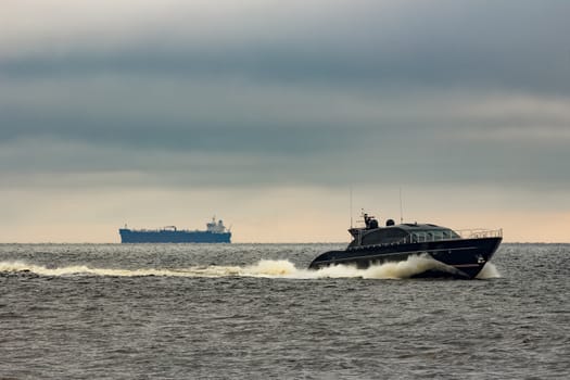 Black elite speed motor boat moving fast from Baltic sea