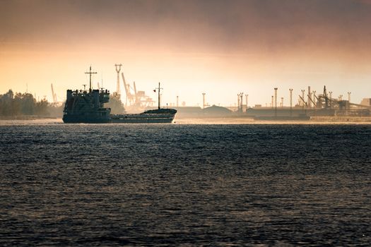 Cargo ship silhouette entering a port of Riga at the morning