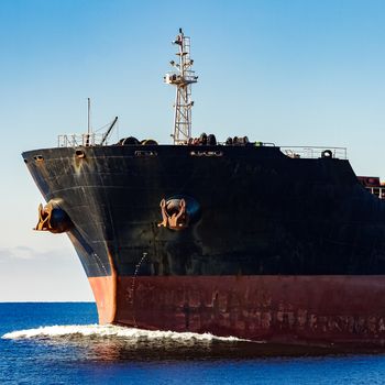 Black cargo ship's bow in still water. Riga, Europe