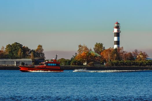 Red pilot ship moving past the lighthouse in Riga