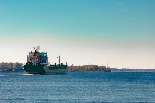 Green cargo ship entering a port of Riga, Europe