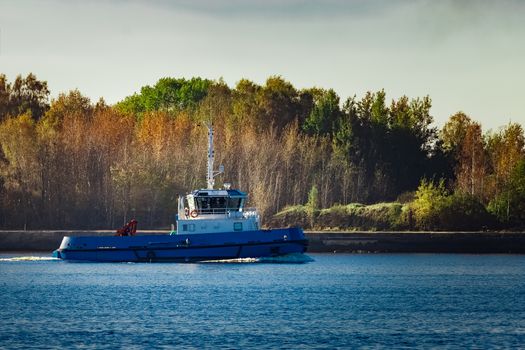 Blue small tug ship leaving Riga and entering the Baltic sea