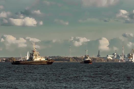 Two tug ships are accepting cargo vessel at Daugava river